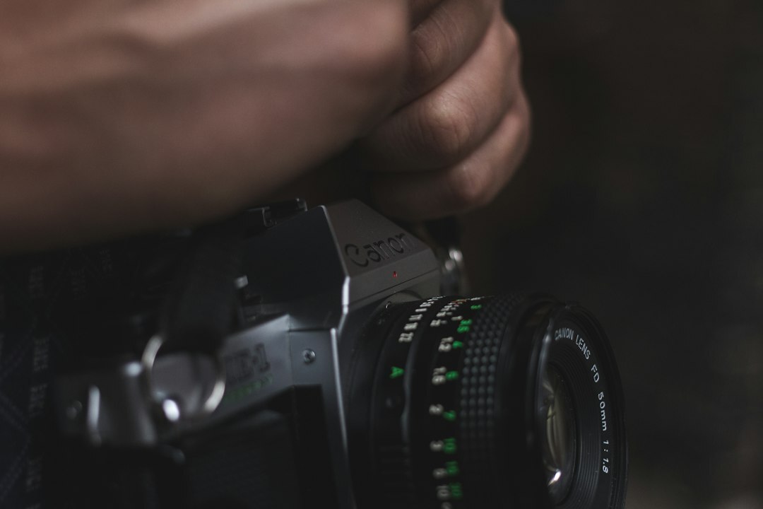 Close-up of hands adjusting a vintage film camera lens